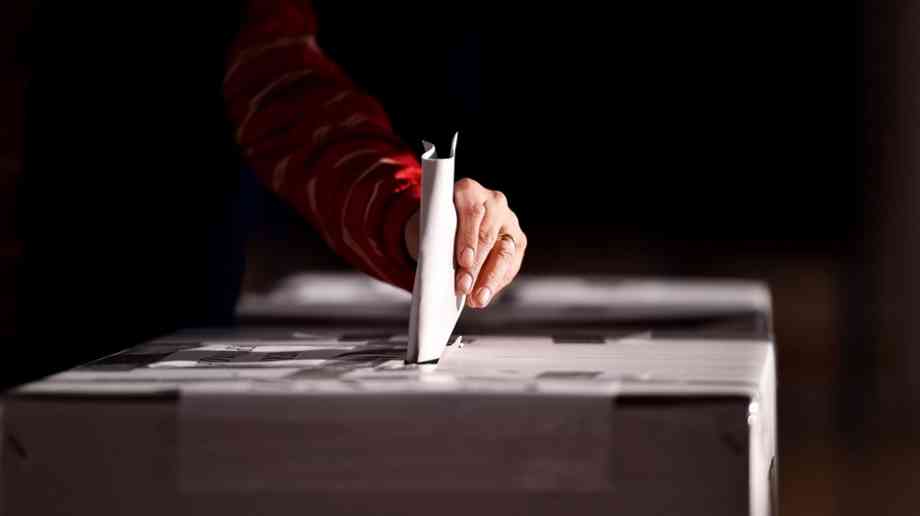 Hand casting a vote into the ballot box Hand casting a vote into the ballot box