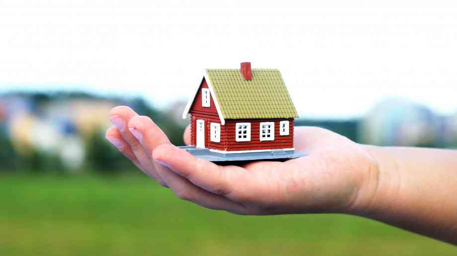 Hand holding a model house.